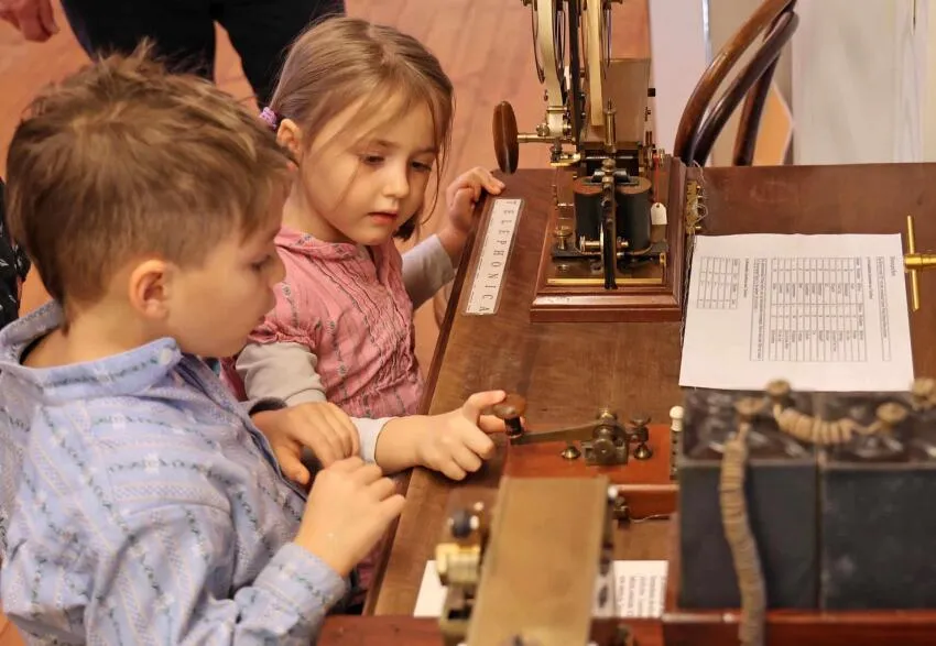 deux enfants découvrent une ancienne machine à écrire dans un musée